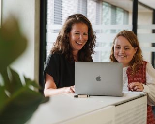 Twee medewerkers van Merk-Echt kijken naar laptop over patent naam controleren