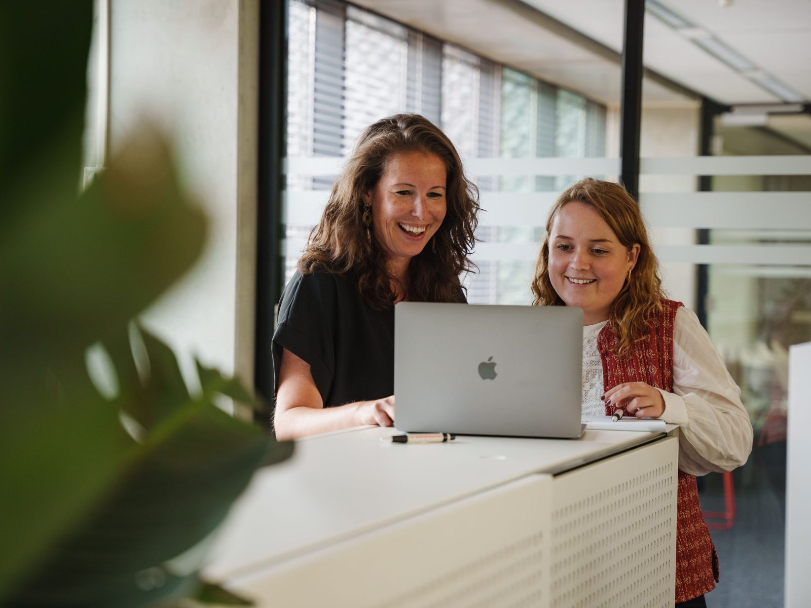 Twee medewerkers van Merk-Echt kijken naar laptop over patent naam controleren