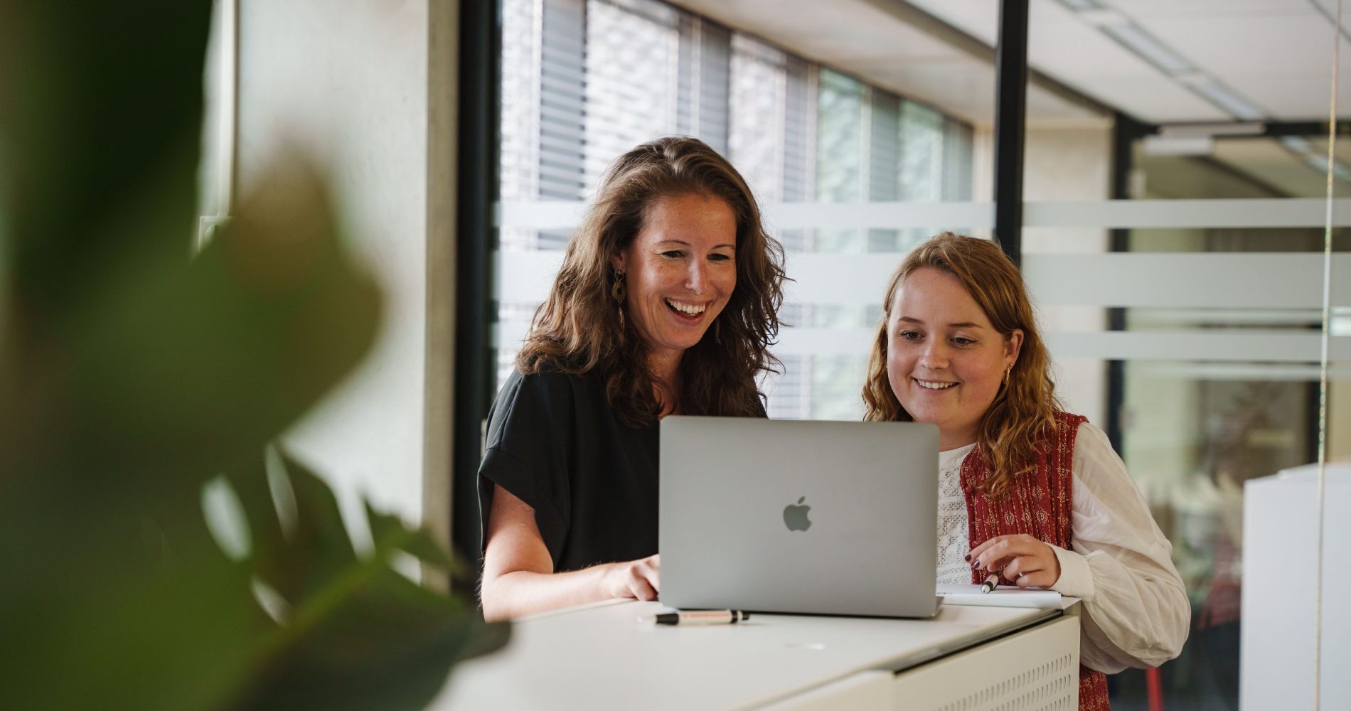 Twee medewerkers van Merk-Echt kijken naar laptop over patent naam controleren